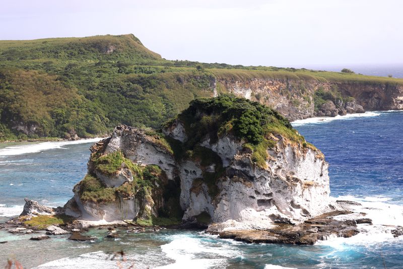 Bird Island, a white limestone islet ringed by surf below green cliffs on the north coast of Saipan
